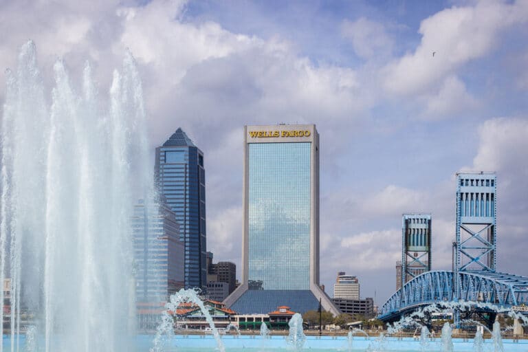 Friendship Fountain lit up at dusk on the Jacksonville riverwalk with the city skyline behind it